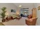 Well-lit living room featuring wicker furniture, neutral decor, and views of the outdoor pool area at 5868 Jefferson Rd, Venice, FL 34293