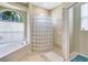 Modern bathroom showcasing a glass block wall, soaking tub, and neutral tile flooring at 622 Pine Ranch East Rd, Osprey, FL 34229