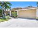 Beige single-story home with a large two-car garage, arched entryway, and well-maintained landscaping at 622 Pine Ranch East Rd, Osprey, FL 34229