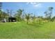 Large, well-maintained backyard featuring lush green grass, a metal garage, and tropical landscaping at 66 Statler St, Port Charlotte, FL 33954
