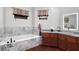 Well-lit bathroom with a soaking tub, dual windows, and dark wood cabinets at 66 Statler St, Port Charlotte, FL 33954