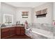 Well-lit bathroom with a soaking tub, dual windows, and dark wood cabinets at 66 Statler St, Port Charlotte, FL 33954