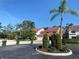 Exterior view features the home's spacious driveway, red-tile roof, and lush landscaping at 7560 Fairway Woods Dr # 305, Sarasota, FL 34238