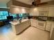 Open-concept kitchen features white cabinetry, modern appliances, and a breakfast bar at 7560 Fairway Woods Dr # 305, Sarasota, FL 34238