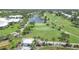 Overhead view of a scenic golf course featuring a tranquil lake with a fountain, lush greens, and palm-lined paths at 819 Montrose Dr # 102, Venice, FL 34293