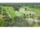 Aerial view of a lush green golf course with a scenic lake, mature trees and manicured fairways on a sunny day at 819 Montrose Dr # 102, Venice, FL 34293