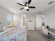 Bright bedroom with colorful floral bedding, a ceiling fan, and a desk area with a plush chair at 8304 Shooting Star Rd, Sarasota, FL 34241
