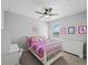 Bright bedroom features a ceiling fan and bed with colorful patterned bedding and a pink themed desk at 8304 Shooting Star Rd, Sarasota, FL 34241