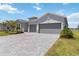 Modern home with a gray three car garage and paved driveway, plus lush landscaping at 8529 Saint Kitts Cir, Englewood, FL 34224