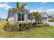 Beautiful front exterior showcasing manicured lawn, elegant stonework, lush plants, and a tranquil lakeside view at 8529 Saint Kitts Cir, Englewood, FL 34224