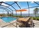 Screened-in pool with a dining table, offering a picturesque lake view at 8529 Saint Kitts Cir, Englewood, FL 34224