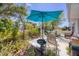 Charming patio area with a blue umbrella, outdoor seating, a small birdbath, and beautiful flowering plants surrounding the space at 8701 Pickwick Rd, North Port, FL 34287