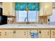 Bright kitchen sink with neutral countertops, wooden cabinets, and tiled backsplash at 881 Grado Dr, Venice, FL 34285