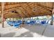 A spacious outdoor seating area with tables and chairs, shaded by a tropical-style palapa roof, perfect for gatherings at 881 Grado Dr, Venice, FL 34285