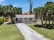 Charming home featuring a well-manicured lawn, mature palm trees, and a long driveway at 929 Cypress Ave, Venice, FL 34285