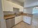 A kitchen with white cabinets, tile floors, stainless steel appliances, and a window view to the backyard at 98 Maltby St, Port Charlotte, FL 33953