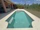 Backyard rectangular pool surrounded by gray concrete deck and lush landscape at 98 Maltby St, Port Charlotte, FL 33953