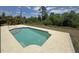 Backyard rectangular pool featuring a gray concrete deck and surrounding vegetation at 98 Maltby St, Port Charlotte, FL 33953