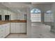 Bright bathroom features a soaking tub under an arched window, and double vanity at 1037 Beckley Cir, Venice, FL 34292