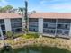 Condo Building with screened lanais overlooks lush landscaping and pond at 1156 Bird Bay Way # 104, Venice, FL 34285