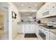 Galley kitchen features granite countertops, modern appliances and bright white cabinets at 1156 Bird Bay Way # 104, Venice, FL 34285