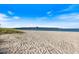 Sandy beach leading to a long pier under a bright blue sky with wispy clouds at 1156 Bird Bay Way # 104, Venice, FL 34285