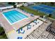 Community pool with blue lounge chairs, tables, and umbrellas, surrounded by manicured landscaping and tennis courts at 1156 Bird Bay Way # 104, Venice, FL 34285