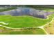 Aerial view of a meticulously maintained golf course with lush green fairways, palm trees, and a scenic lake at 12548 Wellen Golf St, Venice, FL 34293
