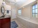 Bright bathroom featuring a soaking tub, tiled floor, double-paned windows, and a spacious vanity at 13314 Prentice Ave, Port Charlotte, FL 33953