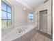 Bright bathroom featuring a soaking tub, walk-in shower, tiled floor, and double-paned windows at 13314 Prentice Ave, Port Charlotte, FL 33953