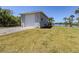 Exterior shot of large garage with three garage doors, surrounded by palms and grass at 13314 Prentice Ave, Port Charlotte, FL 33953