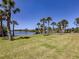 Waterfront property with lush green grass and many palm trees, perfect for relaxing at 13314 Prentice Ave, Port Charlotte, FL 33953