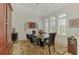Dining room with glass table, colorful rug, and ample natural light through arched windows with white shutters at 138 Rimini Way, North Venice, FL 34275