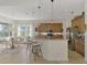 Open floor plan featuring the kitchen with tan cabinets and dining area with glass table and woven chairs at 138 Rimini Way, North Venice, FL 34275