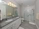 Bathroom featuring double vanity, a large mirror, granite countertops, and walk in shower with glass doors at 13908 Vadini St, Venice, FL 34293