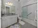 Well-lit bathroom with granite counters, white cabinetry and combination shower and tub with sliding glass doors at 13908 Vadini St, Venice, FL 34293