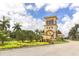 Picturesque community entrance featuring a beautiful tower, lush landscaping, and swaying palm trees at 13908 Vadini St, Venice, FL 34293