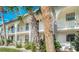 Exterior of condo featuring multiple balconies, white facade, lush green trees, and tropical landscaping at 1730 Manasota Beach Rd # 212, Englewood, FL 34223