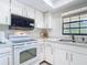 Updated kitchen featuring white appliances, white cabinets, updated counters, and a stainless steel sink at 1730 Manasota Beach Rd # 212, Englewood, FL 34223