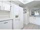 Kitchen features white cabinets, white appliances, neutral counters, and gray wood floors at 1730 Manasota Beach Rd # 212, Englewood, FL 34223
