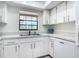 Bright kitchen features white cabinetry, stainless steel sink, neutral countertops, and views of the trees outside at 1730 Manasota Beach Rd # 212, Englewood, FL 34223