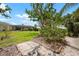 Landscaped backyard featuring mature trees, shrubs, with a view of the screened-in pool area at 1833 Raintree Ln, Venice, FL 34293