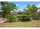 Lush backyard showcasing mature trees, shrubs, and landscaping; a screened-in pool is visible at 1833 Raintree Ln, Venice, FL 34293