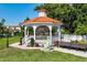 A charming gazebo with a red tile roof, surrounded by green grass and tropical foliage at 1833 Raintree Ln, Venice, FL 34293