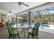 Inviting screened lanai with a glass table and seating, offering views of the pool and serene backyard oasis at 1833 Raintree Ln, Venice, FL 34293