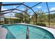 Sparkling in-ground pool with a screened enclosure, surrounded by lush greenery, creating a private backyard retreat at 1833 Raintree Ln, Venice, FL 34293