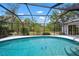 Beautiful in-ground pool with screened enclosure, offering a tranquil view of the manicured backyard and clear blue sky at 1833 Raintree Ln, Venice, FL 34293