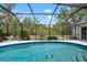 Inviting in-ground pool with a screened enclosure, surrounded by lush landscaping, offering a private oasis at 1833 Raintree Ln, Venice, FL 34293