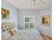 Bright bedroom featuring a queen bed with floral bedding, light blue walls, and a ceiling fan at 1892 San Silvestro Dr, Venice, FL 34285