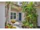 Charming home entrance with a blue door surrounded by tropical landscaping at 1892 San Silvestro Dr, Venice, FL 34285